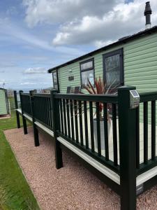 a green trailer with two benches in front of it at Beach View Eden Heights Kinkell Braes 2 bedrooms 2 bathrooms in St. Andrews