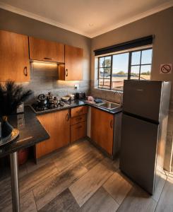 a kitchen with wooden cabinets and a black refrigerator at Rudman's Private Love Nest in Boksburg