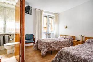 a bedroom with two beds and a toilet and a window at Hostal Oria in Luarca