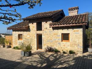 a stone house with a tile roof on a patio at La ferme des Soudanières in Ceyzériat +16 photos