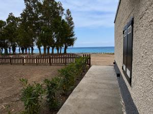 a sidewalk next to a building with a fence and the ocean at L'imbarco ROOMS in Badolato Stazione