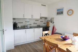 a kitchen with white cabinets and a wooden table at Kustverhuur, Park Schoneveld, Zeemeeuw 138 in Breskens