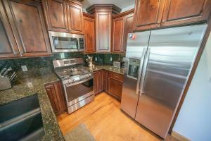 a kitchen with wooden cabinets and a stainless steel refrigerator at Starfire 1979 by SummitCove Lodging in Colorado in Keystone