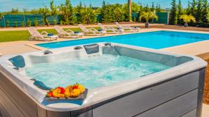 a hot tub with fruit in it next to a pool at Villa Paradise - Moradia tranquila com piscina aquecível e BBQ - Albufeira in Lagoa