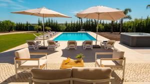 a swimming pool with chairs and umbrellas next to a pool at Villa Paradise - Moradia tranquila com piscina aquecível e BBQ - Albufeira in Lagoa +42 photos