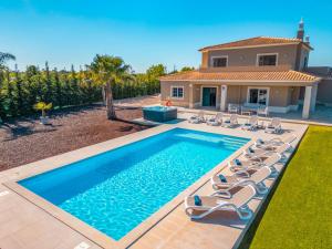 a swimming pool with chairs and a house at Villa Paradise - Moradia tranquila com piscina aquecível e BBQ - Albufeira in Lagoa