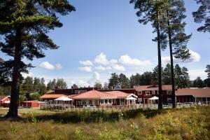 a large red building with trees in the background at Hotell Moskogen in Leksand