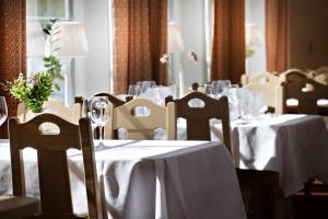 a dining room with tables and chairs with white table cloth at Hotell Moskogen in Leksand +42 photos