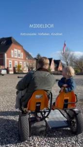 a man riding a toy motorcycle with a child on it at Bauernhuus 5 in Fehmarn