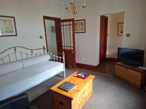 a living room with a couch and a table and a tv at De Kothuize 6 in Graaff-Reinet
