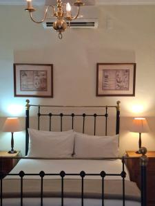 a bedroom with a bed with two lamps and a chandelier at De Kothuize 6 in Graaff-Reinet +2 photos