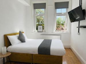 a bedroom with a bed with a television and two windows at Endsleigh Park Hotel in Hull