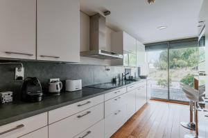 a kitchen with white cabinets and a large window at Ocean Village Eden in Troia