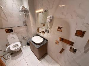 a white bathroom with a toilet and a sink at Hotel Rosewood in Prayagraj