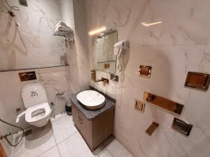 a white bathroom with a toilet and a sink at Hotel Rosewood in Prayagraj