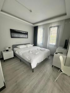 a white bedroom with a large bed and a chair at Cicek Apart Hotel in Çeşme +51 photos