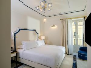 a bedroom with a white bed and a blue chair at Hotel du Tasso Sorrento in Sorrento