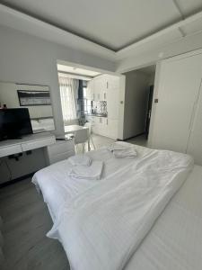 a white bedroom with a large bed and a desk at Cicek Apart Hotel in Çeşme