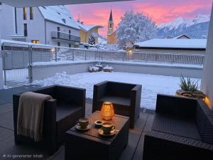 a patio with two chairs and a table in the snow at Apartment Bruneck Central in Brunico