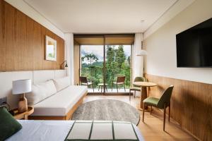 a hotel room with a couch and a tv at Hotel Vila Inglesa in Campos do Jordão