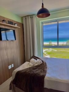 a bedroom with a bed with a view of the ocean at Flat Mandai Cabo Frio in Cabo Frio +111 photos