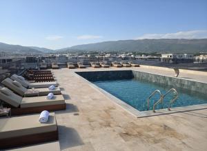 a swimming pool on the roof of a building with chairs at Uma Premium in Ulcinj
