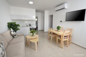 a living room with a couch and a table and a kitchen at MeravSuite in Migdal