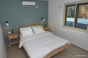 a bedroom with a bed with white sheets and a window at MeravSuite in Migdal