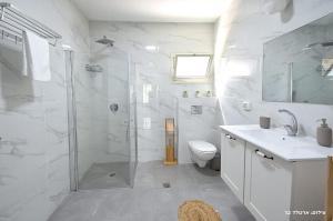 a white bathroom with a shower and a toilet at MeravSuite in Migdal +11 photos