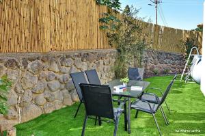 a table and chairs in a yard with a stone wall at MeravSuite in Migdal