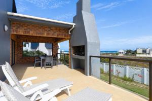 a balcony with white chairs and a table and the ocean at Cosy House in Yzerfontein