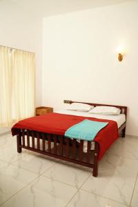 a bedroom with a bed with a red and blue blanket at Twilight Stays Cherai Beach in Pallipuram