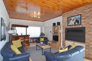 a living room with blue couches and a flat screen tv at Cosy House in Yzerfontein