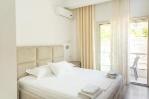 a bedroom with a bed with white sheets and a window at Le Monde 2 in Borsh
