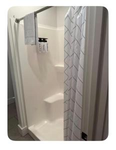 a shower with a white shower curtain in a bathroom at Sleep at Simplicity in Massena