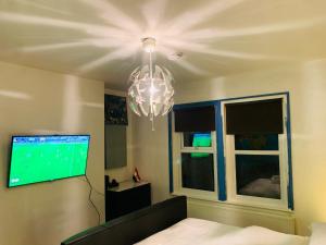 a living room with a chandelier and a tv at Blue Room in Ifield