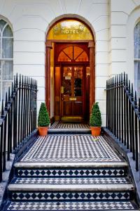 a front door of a hotel with two potted plants at Avonmore Hotel in London