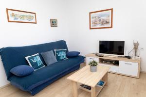 a living room with a blue couch and a tv at Sea View apartment 50 m from St Rok Beach in Pučišća