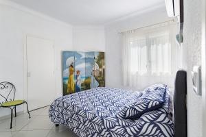 a white bedroom with a bed and a painting at Mer Vue Sublime in Canet-en-Roussillon