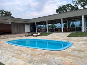 a blue swimming pool in front of a house at Vistas de Gravatá in Gravatal