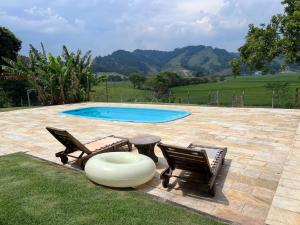a swimming pool with two chairs and a table at Vistas de Gravatá in Gravatal