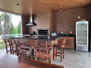 a kitchen with a bar with wooden chairs and a refrigerator at Vistas de Gravatá in Gravatal