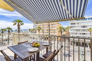 a table on a balcony with a view of a building at Mer Vue Sublime in Canet-en-Roussillon