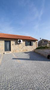 a stone house with a brick driveway in front of it at As Casas do Penedo da Moura in Arcos de Valdevez