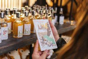 a woman holding up a book in front of bottles of alcohol at Hostal Boutique Factoria Patagonia in Puerto Natales