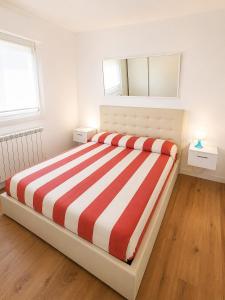 a bedroom with a bed with a red and white striped blanket at Casa Incanto - Agenzia Cocal in Caorle