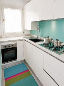 a kitchen with white cabinets and a rainbow rug at Casa Incanto - Agenzia Cocal in Caorle