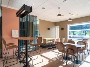 a waiting room with tables and chairs and a flat screen tv at B&B HOTEL Concarneau Keriolet in Concarneau
