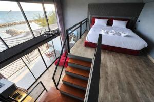 a bedroom with a bed and a staircase with a view of the ocean at Beachside Hotel H8 in Ban Nong Si Tong