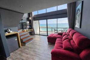 a living room with a red couch and a view of the ocean at Beachside Hotel H8 in Ban Nong Si Tong